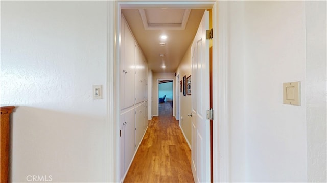 hallway with attic access and light wood-type flooring