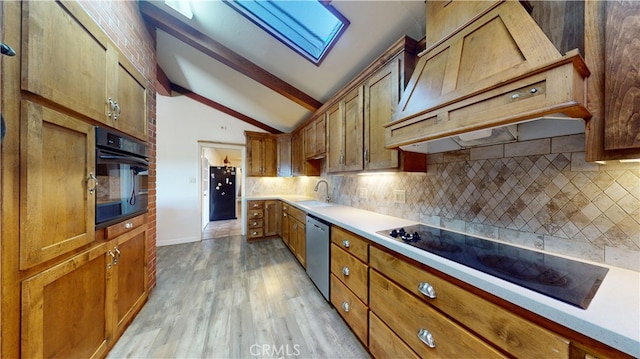 kitchen with custom exhaust hood, a sink, black appliances, lofted ceiling with skylight, and tasteful backsplash