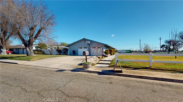 ranch-style house featuring an outbuilding, concrete driveway, a front yard, and fence