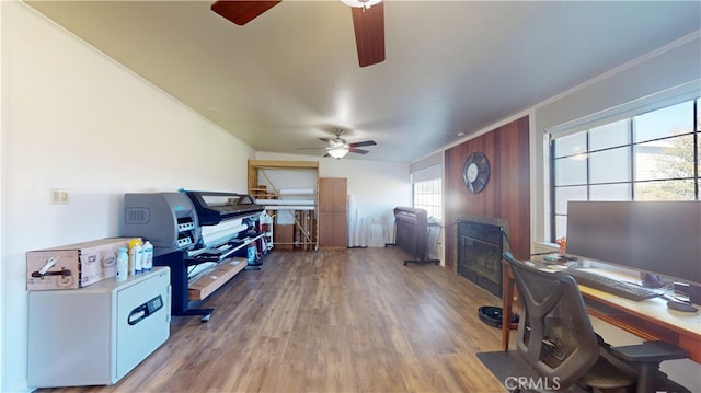 office area featuring a glass covered fireplace, wood finished floors, a ceiling fan, and crown molding