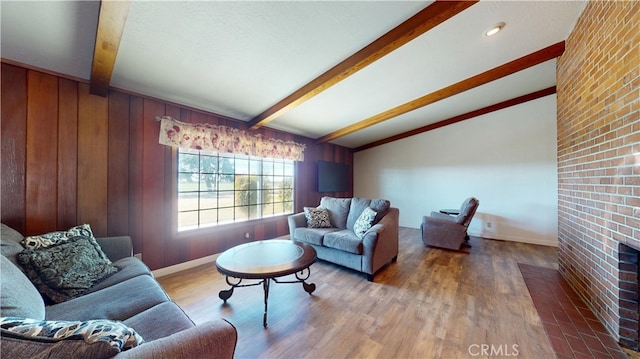 living room with lofted ceiling with beams, baseboards, wooden walls, and wood finished floors