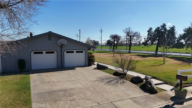 garage with concrete driveway and fence