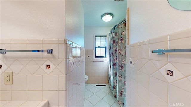 bathroom with a shower with curtain, tile walls, toilet, and tile patterned flooring