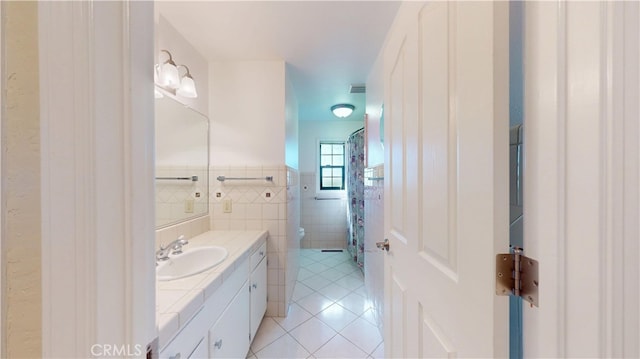 bathroom featuring vanity, visible vents, tile patterned floors, toilet, and tile walls