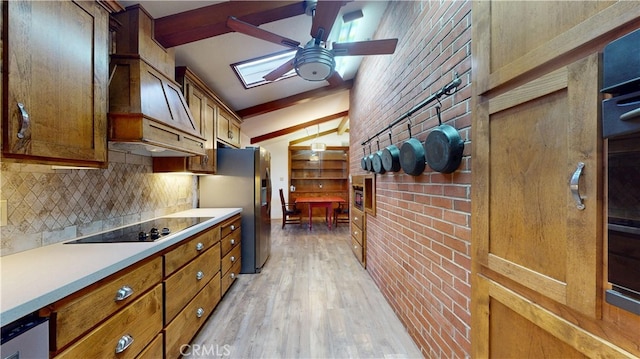 kitchen featuring tasteful backsplash, black electric cooktop, brown cabinets, light wood-style floors, and a ceiling fan