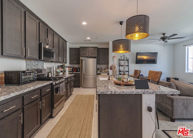 kitchen featuring pendant lighting, a kitchen bar, dark brown cabinetry, stainless steel appliances, and a center island with sink