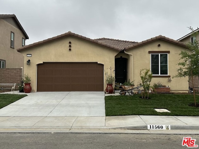 mediterranean / spanish-style house featuring a garage and a front yard