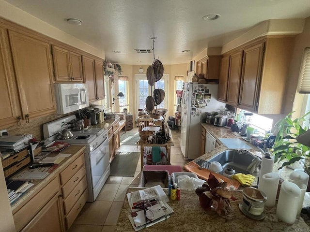 kitchen with light tile patterned floors, white appliances, and decorative light fixtures