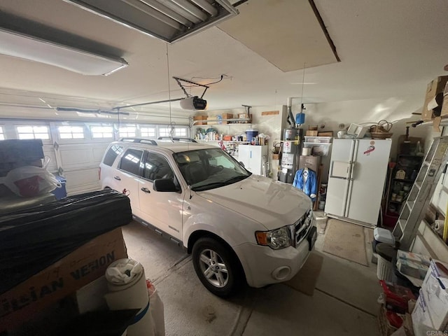 garage featuring white refrigerator, a garage door opener, and gas water heater