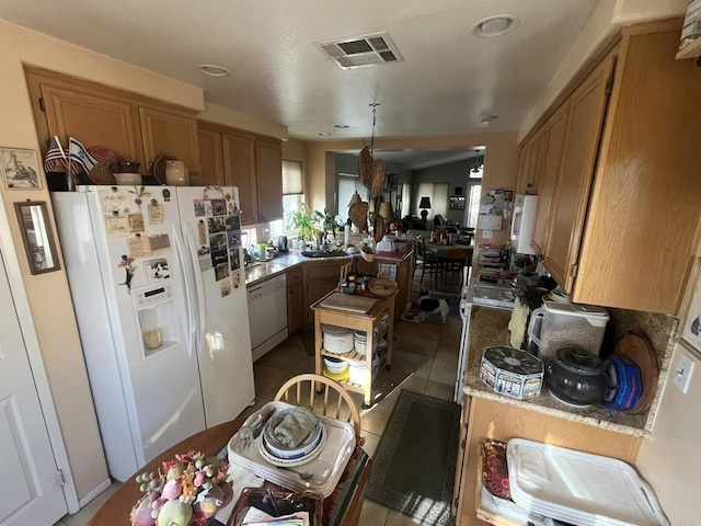 kitchen featuring white appliances, kitchen peninsula, and light tile patterned floors