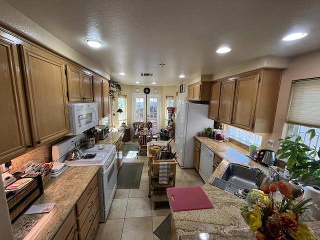 kitchen featuring light tile patterned floors, light countertops, visible vents, a sink, and white appliances