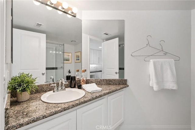 full bathroom with an enclosed shower, visible vents, and vanity