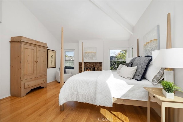 bedroom with lofted ceiling, a fireplace, and hardwood / wood-style floors