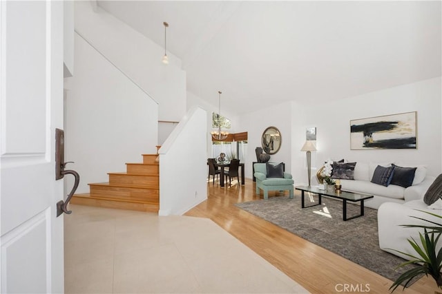 living room featuring a chandelier, high vaulted ceiling, and light wood-type flooring