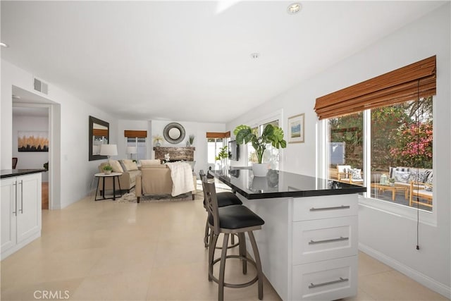 kitchen featuring dark countertops, a breakfast bar, visible vents, and white cabinets