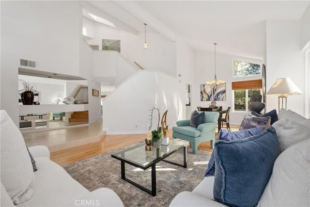 living room with hardwood / wood-style floors, a notable chandelier, and high vaulted ceiling