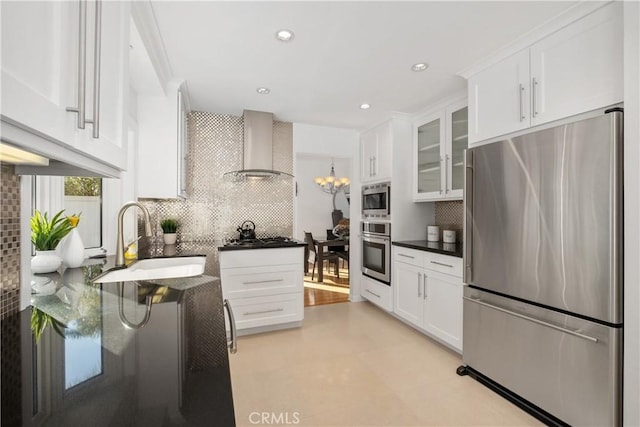 kitchen featuring wall chimney exhaust hood, appliances with stainless steel finishes, a sink, and white cabinets