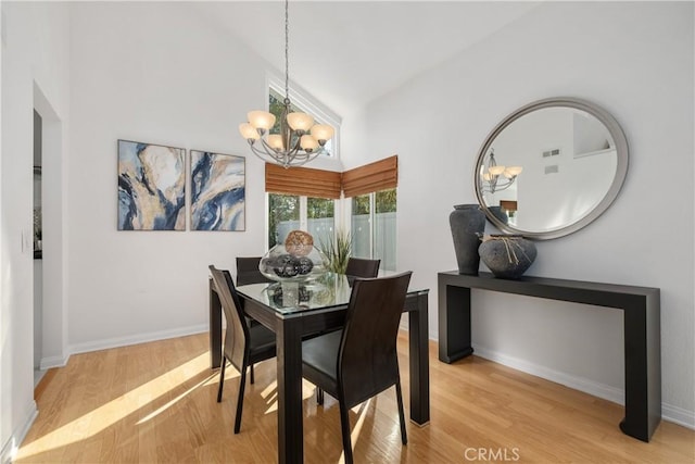 dining space featuring high vaulted ceiling, a notable chandelier, and light hardwood / wood-style floors