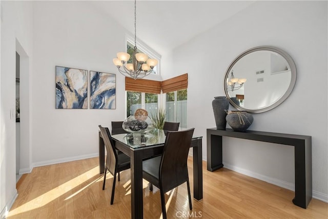 dining room featuring a chandelier, light wood-style floors, high vaulted ceiling, and baseboards