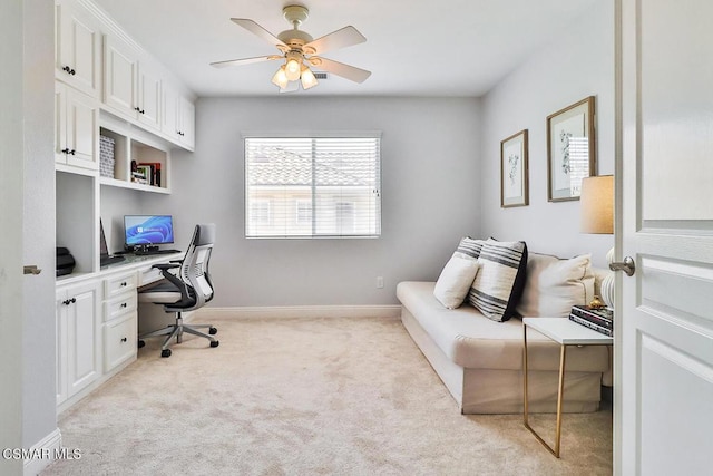 office space with built in desk, light colored carpet, and ceiling fan