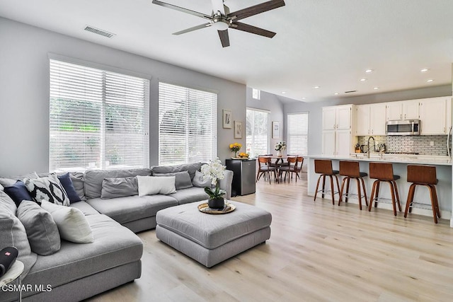 living room with sink, light hardwood / wood-style floors, and ceiling fan