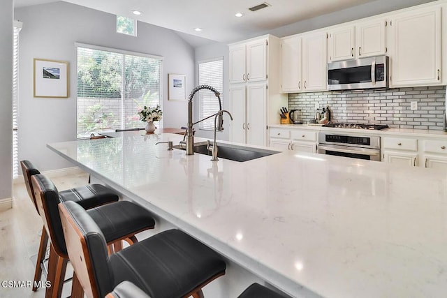 kitchen featuring stainless steel appliances, a breakfast bar, sink, and white cabinets