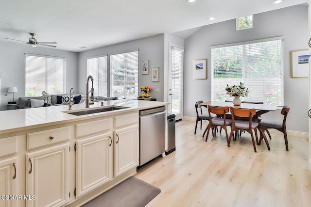 kitchen featuring sink, vaulted ceiling, light hardwood / wood-style flooring, dishwasher, and cream cabinetry