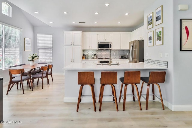 kitchen with appliances with stainless steel finishes, a breakfast bar, and white cabinets