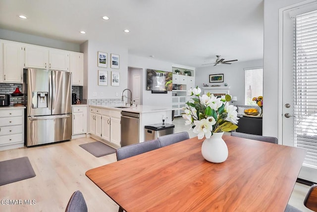 dining area featuring sink, ceiling fan, and light wood-type flooring