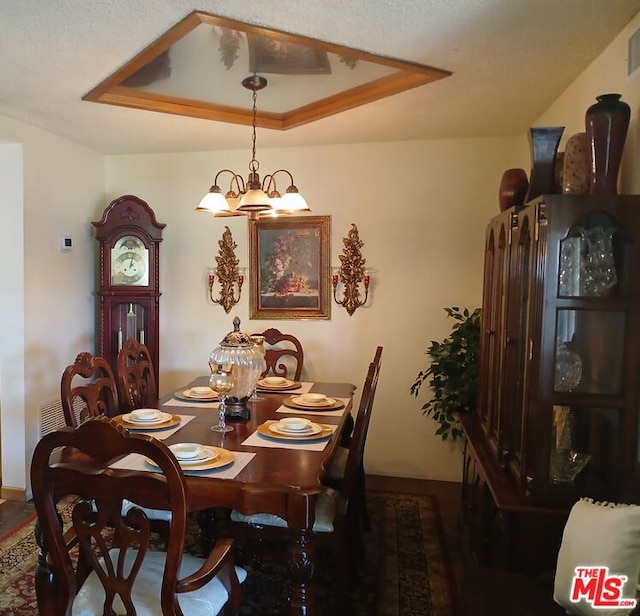 dining space featuring a raised ceiling and an inviting chandelier