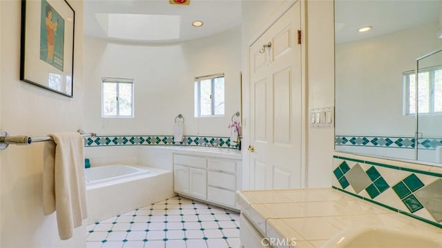 bathroom featuring vanity, a relaxing tiled tub, and tile walls