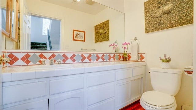 bathroom featuring vanity, decorative backsplash, and toilet