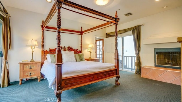 carpeted bedroom with a tiled fireplace