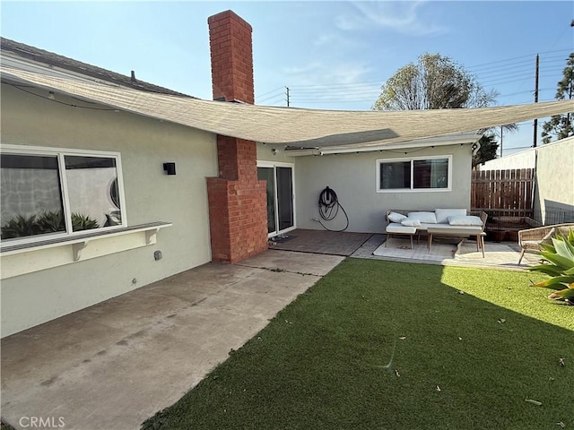 rear view of property with fence, a yard, stucco siding, a patio area, and an outdoor hangout area