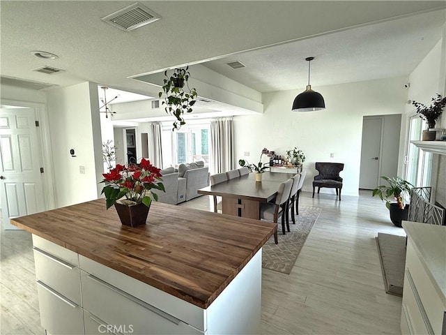 dining area with visible vents, light wood-style flooring, and a textured ceiling