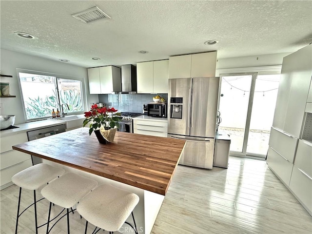 kitchen with a sink, stainless steel appliances, light wood-style floors, and visible vents