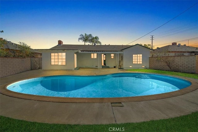 pool at dusk featuring a patio