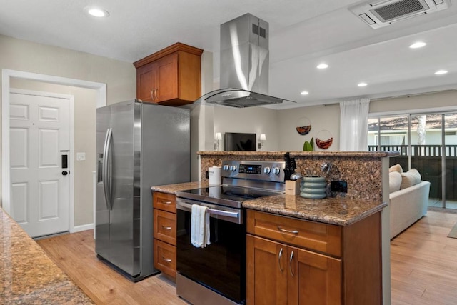 kitchen with island range hood, light hardwood / wood-style flooring, stainless steel appliances, and dark stone counters