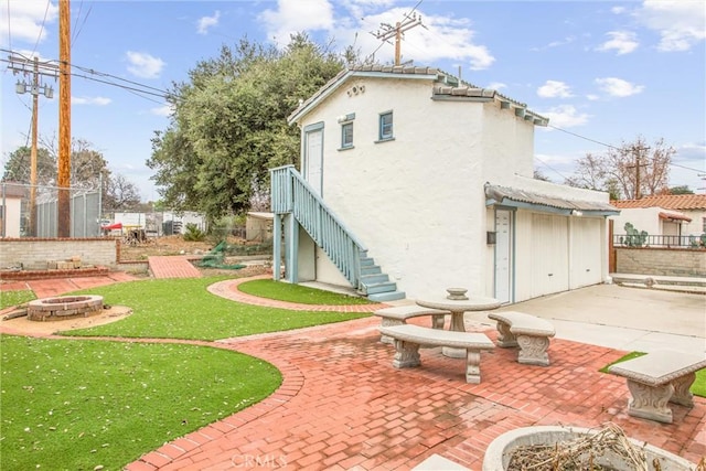 rear view of property with an outdoor fire pit, a patio area, and a lawn