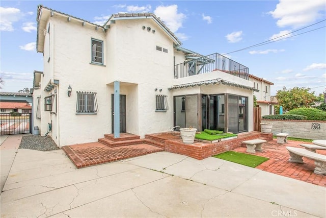 back of property with a balcony and a patio area