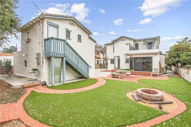 rear view of house featuring a balcony, a patio area, a fire pit, and a lawn