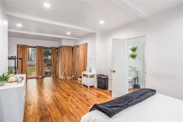 bedroom featuring ensuite bath, beam ceiling, and hardwood / wood-style floors