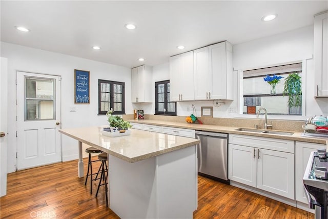 kitchen featuring white cabinetry, sink, a breakfast bar area, a center island, and stainless steel dishwasher