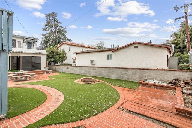 view of yard with a balcony, a patio area, and an outdoor fire pit