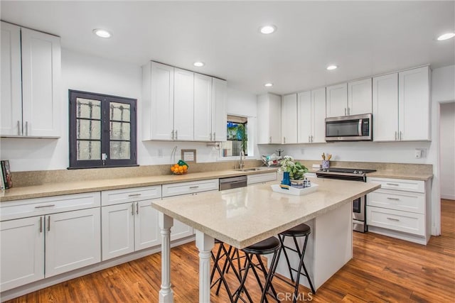 kitchen featuring appliances with stainless steel finishes, white cabinets, and a kitchen breakfast bar