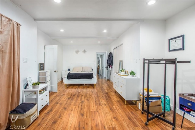 bedroom with beam ceiling and light hardwood / wood-style flooring