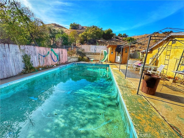 view of swimming pool featuring a fenced backyard and a water slide