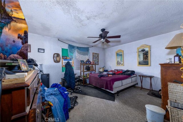 carpeted bedroom featuring a ceiling fan and a textured ceiling