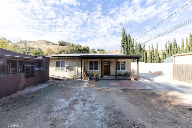 view of front of home with a patio area, fence, and stucco siding