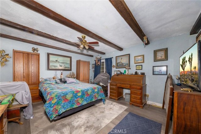 bedroom featuring ceiling fan, beamed ceiling, light wood-type flooring, and baseboards